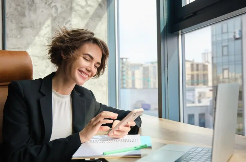 A happy businesswoman looking at her cell phone