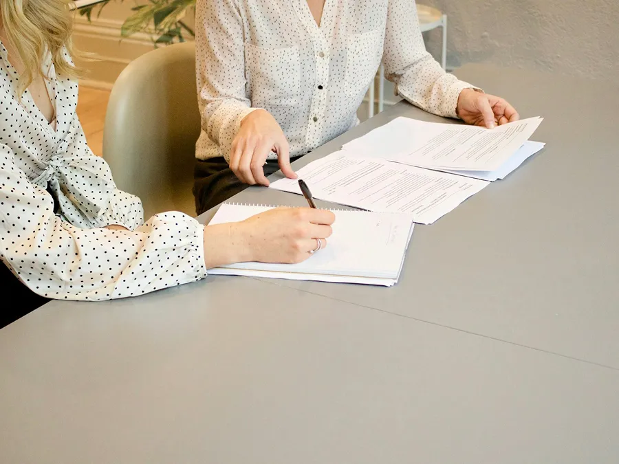 Two people sitting and signing documents